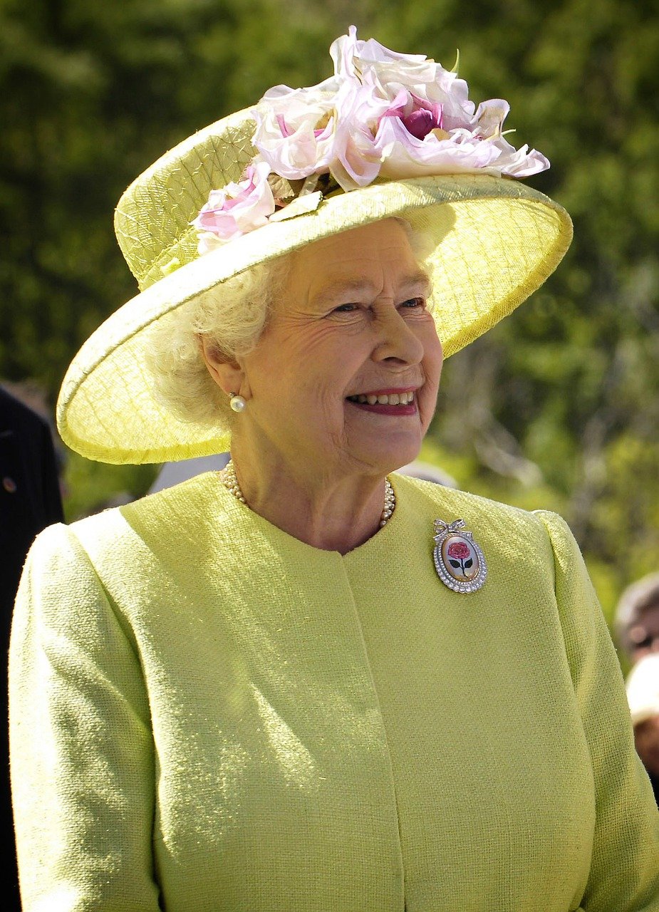 Queen-Elizabeth-II.-lächelnd-in-gelbem-oberteil-und-gelbem-Blumenhut- Journalismus-Pfundtner